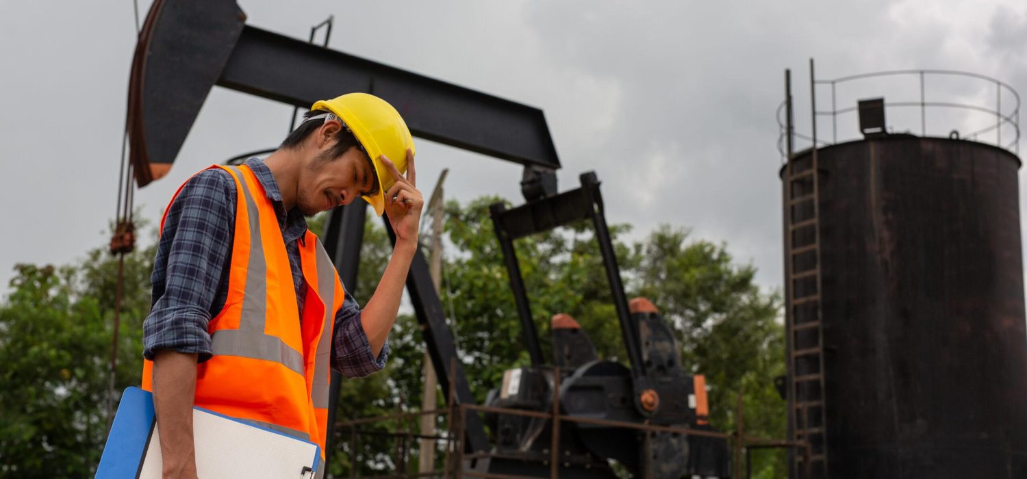Workers standing and checking beside working oil pumps.