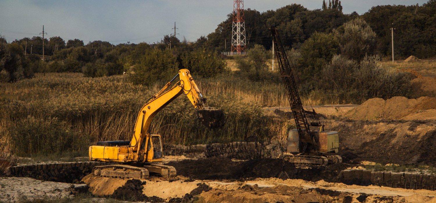 A closeup shot of an ongoing construction  with tracks and a bulldozer on an  abandoned land
